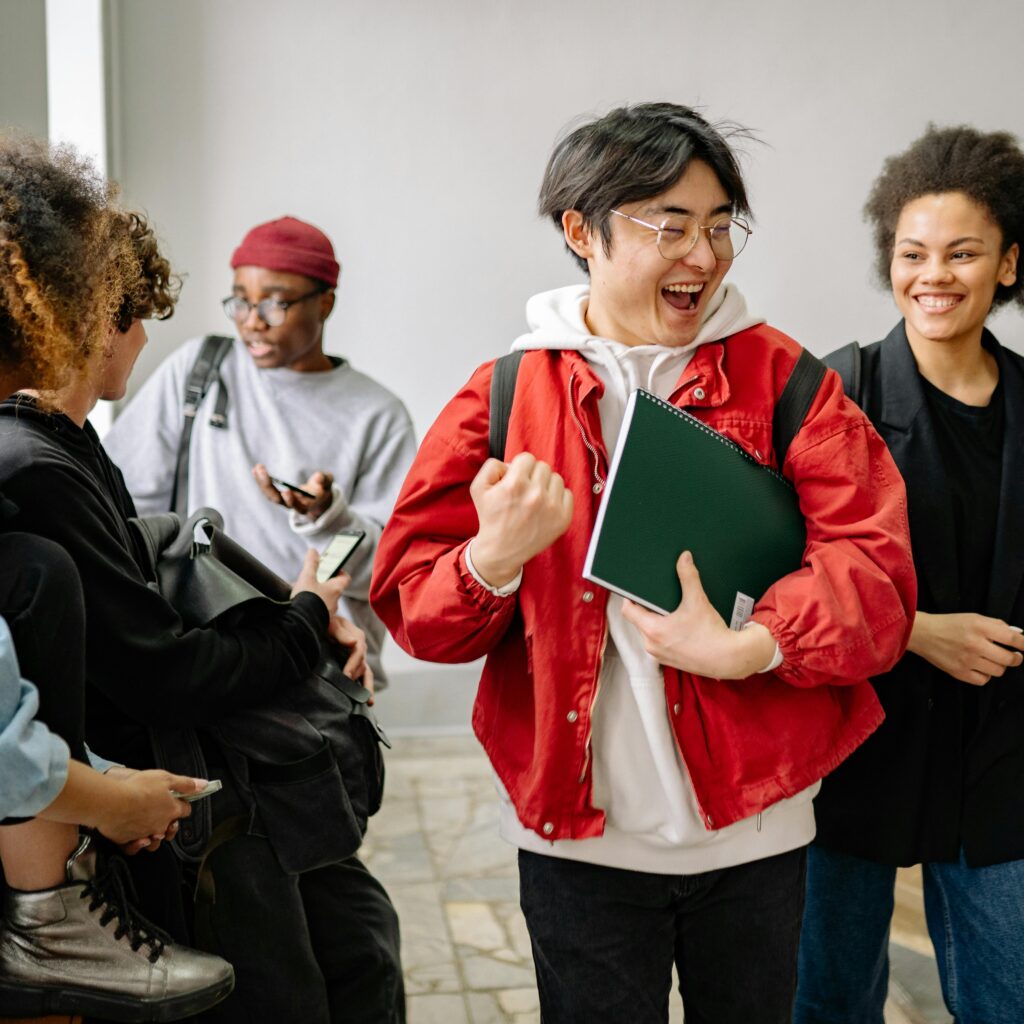 A group of diverse college students happily interacting indoors, showcasing friendship and diversity in a university setting.